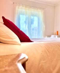 uma cama com almofadas vermelhas e brancas e uma janela em Appartement T2 avec vue panoramique sur la côte em Atouguia da Baleia