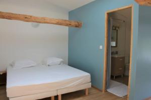 a bedroom with a white bed and a blue wall at Grange Labarthessié in Briatexte