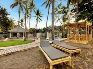 a backyard with two beds and a pavilion with palm trees at Lilin Lovina Beach Hotel in Lovina
