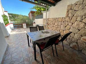 einen Tisch und Stühle auf einer Terrasse mit einer Steinmauer in der Unterkunft Apartments Peronja Jelsa Seafront in Jelsa