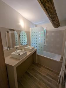 een badkamer met 2 wastafels, een spiegel en een bad bij La ferme du TourreBlanc in Lambesc