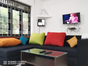 a living room with a black couch with colorful pillows at Bee Cottage Negombo in Negombo