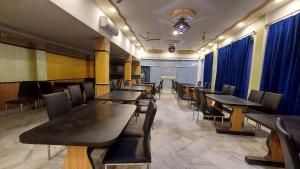 una sala da pranzo con tavoli, sedie e tende blu di Swastik Resort Tajpur a Tajpur