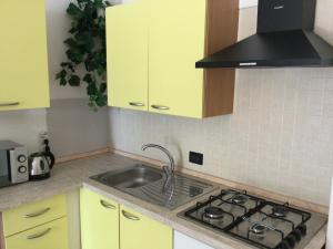 - une cuisine avec des placards jaunes et un évier dans l'établissement Residence Porto Miggiano, à Santa Cesarea Terme
