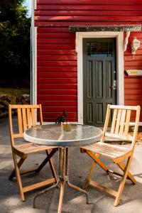 Brattholmen的住宿－VILLA BRATTHOLMEN，红色建筑前的两把椅子和一张桌子
