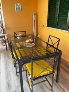 a dining room table with two yellow chairs and a glass table at Charming Townhouse with Garden in Impruneta