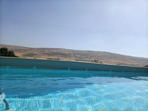 a large pool of blue water with mountains in the background at בגג העמק - וילה in HaZore‘im