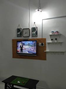 a tv on a wall in a room with a table at Rumah Tamu FieSari Jeli M U S L I M in Jeli