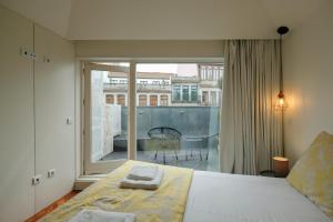 ein Schlafzimmer mit einem Bett und einem großen Fenster in der Unterkunft Impar Luxury Apartments in Porto