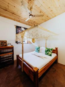a bedroom with a canopy bed with a wooden ceiling at The Kichwa House in Kiwengwa