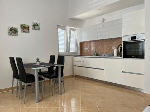 uma cozinha com armários brancos e uma mesa e cadeiras em Apartmani Emil em Trogir