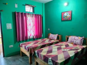 two beds in a room with green walls at MangalMurti Himalyan Hotel in Almora
