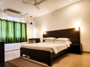 1 dormitorio con 1 cama grande y cortinas verdes en Hotel Rajwada Aurangabad, en Aurangabad
