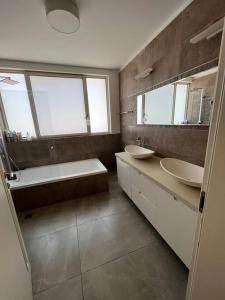 a bathroom with two sinks and a tub and two mirrors at Kosher Luxury villa - Raanana in Ra‘ananna