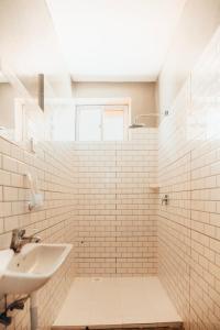 baño de azulejos blancos con lavabo y ventana en The Kichwa House en Kiwengwa