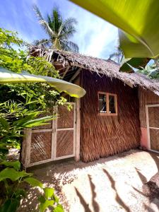 a wooden building with a gate and a palm tree at Secret Pool Villa Tuason Beach in General Luna