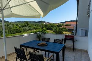 a blue table and chairs on a balcony with an umbrella at LUXURY STYLISH APARTMENT BURE in Murter