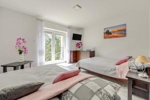 a white bedroom with two beds and a window at POKOJE GOŚCINNE LAWENDOWY DWÓR in Nickelswalde