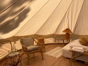 - une chambre avec une tente dotée de chaises et d'un lit dans l'établissement Bådsted Camping, à Gudhjem