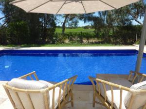 uma mesa e cadeiras com um guarda-sol ao lado de uma piscina em Amande Bed and Breakfast em McLaren Vale