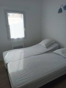 een witte slaapkamer met 2 bedden en een raam bij Maison de vacances 4 personnes in La Tranche-sur-Mer