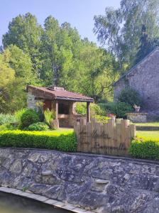 um jardim com uma cerca de madeira e um gazebo em Le Moulin de Benneville chambres d'hôtes, petit déjeuner compris em Cahagnes