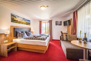 um quarto de hotel com uma cama e um sofá em Pension Gimpl em Siegsdorf