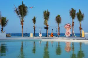 a group of people standing next to a swimming pool with palm trees at iSea by the sea in Ninh Van Bay