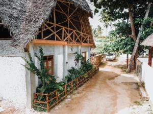 a house with a thatched roof on a dirt road at The Kichwa House in Kiwengwa