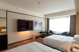 a hotel room with two beds and a flat screen tv at Sheraton Taoyuan Hotel in Dayuan