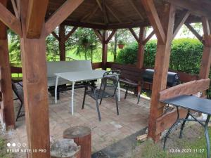 a wooden pavilion with a white table and chairs at Pokoje. Apartament w Oklinach 