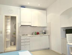 a white kitchen with white cabinets and a counter at Placa Apartments in Mošćenička Draga