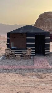 a black and white building with chairs in the desert at Adam Bedouin camp in Wadi Rum