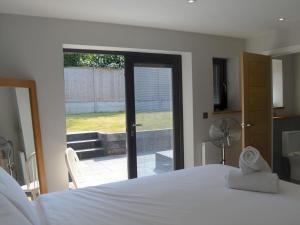 um quarto com uma cama branca e uma porta de vidro deslizante em Pass the Keys Spacious modern lovely bungalow em Bournemouth