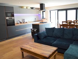 uma sala de estar com um sofá azul e uma cozinha em Pass the Keys Spacious modern lovely bungalow em Bournemouth