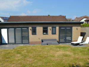 a house with a patio with two chairs and a table at Pass the Keys Spacious modern lovely bungalow in Bournemouth