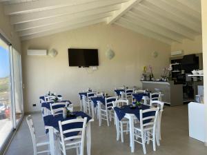 un comedor con mesas azules y sillas blancas en Is Arenas Biancas Agriturismo en Teulada