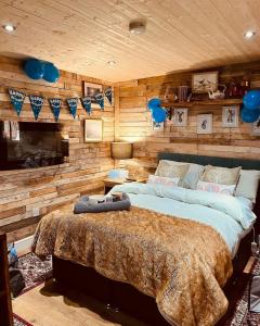 a bedroom with a large bed and wooden walls at LILAC COTTAGE cabin in Swafield