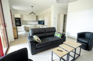 a living room with a black couch and two chairs at Appartement proche du lac centre ville in Soustons