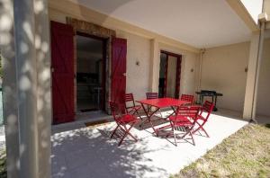 a red table and chairs on a patio at Appartement proche du lac centre ville in Soustons