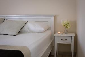 a white bed with a night stand with a vase of flowers at Villa Jakov in Promajna