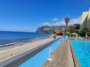 una piscina junto a una playa y el océano en By the Beach & Pool Apartment, en Funchal
