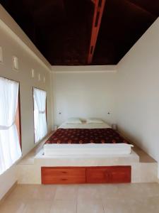 uma cama grande num quarto branco com duas janelas em Sumatra Expedition Lodge em Bukit Lawang