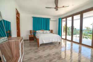 a bedroom with a bed with blue curtains at La Belle Residence Self Catering Accommodation in Beau Vallon