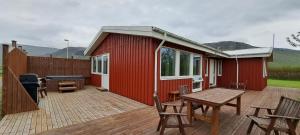 a red shed with a table and chairs on a deck at Ægisholt privete house with hot tub in Patreksfjörður