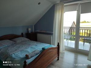 a bedroom with a bed with a view of a balcony at Pokoje. Apartament w Oklinach 