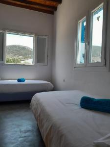 two beds in a room with two windows at Spíti Catharina in Irakleia