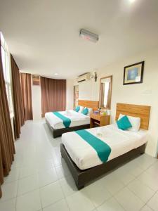 Sun Tree Hotel في Kampong Kerayong: غرفه فندقيه سريرين في غرفه