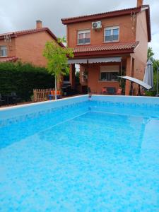 a large blue swimming pool in front of a house at Chalet Las Dalias in El Espinar