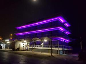 un edificio con luces moradas en él por la noche en KATRINA HOTEL, en Skaramangás